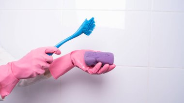 Kadın eli lastik eldiven içinde, temiz yüzey için bez tutuyor.