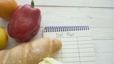 Tahta masa üzerinde boş küçük defterli yiyecek ürünleri, üst manzara.