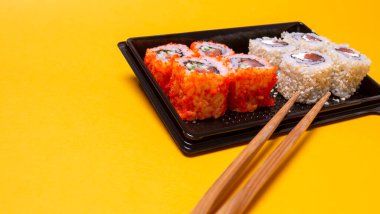 small portion of rolls with fish on an orange background