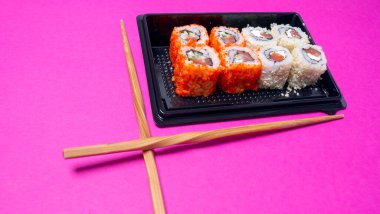 Pembe arka planda balıklı küçük bir rulo.