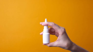 Kadın eli burun spreyi tutuyor.