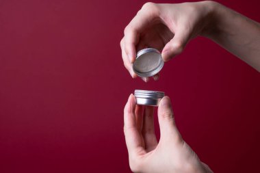 Kadın eli, yuvarlak bir krema paketi açar.