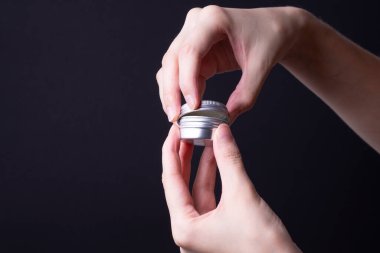 Kadın eli, yuvarlak bir krema paketi açar.