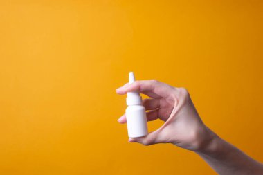 Kadın eli burun spreyi tutuyor.