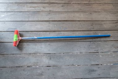 Eski bir yer fırçası, ahşap bir tahtanın üzerinde, uzun saplı..