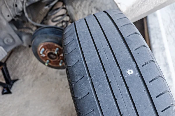 Close up of screw nail puncturing car tire — Stock Photo, Image
