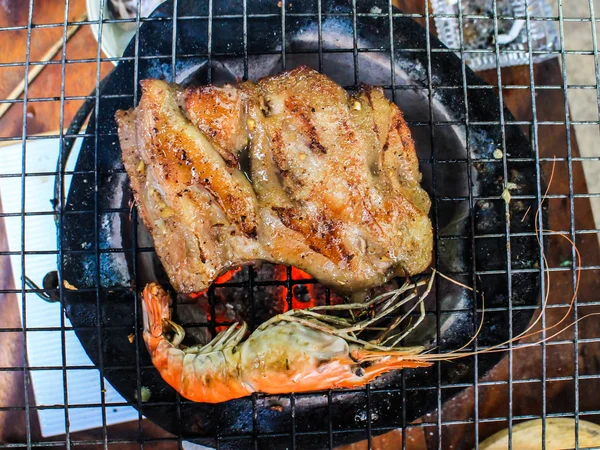 Gegrilde garnalen en gegrild varkensvlees op de vlammende barbecue gril — Stockfoto