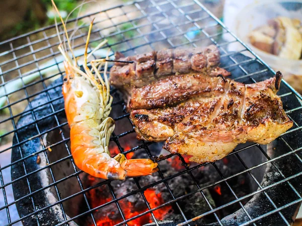 Gegrillte Garnelen und gegrilltes Schweinefleisch auf dem flammenden Grill — Stockfoto