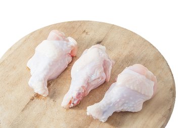 Beyaz arka plan üzerinde ahşap kesme tahtası üzerinde çiğ tavuk budu