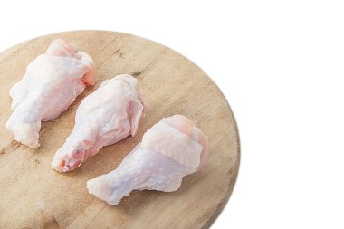 Beyaz arka plan üzerinde ahşap kesme tahtası üzerinde çiğ tavuk budu