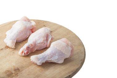 Beyaz arka plan üzerinde ahşap kesme tahtası üzerinde çiğ tavuk budu