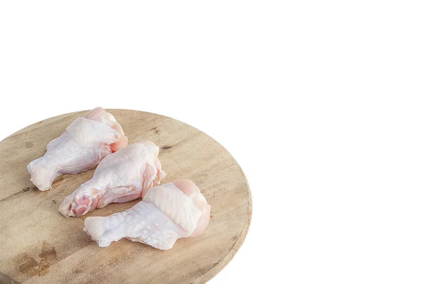 Syrové kuřecí stehýnka na dřevěné krájecí desky na bílém pozadí — Stock fotografie