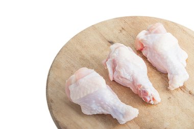 Beyaz arka plan üzerinde ahşap kesme tahtası üzerinde çiğ tavuk budu