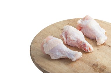 Beyaz arka plan üzerinde ahşap kesme tahtası üzerinde çiğ tavuk budu
