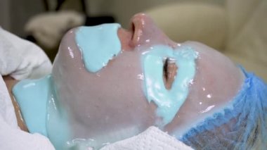  Yüzünde kaplıca maskesi olan bir kadın. Kadın gözlerini kapadı ve gençleşme sürecinin tadını çıkardı.