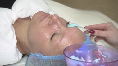 Yanağında kozmetik kil olan orta yaşlı güzel bir kadının portresi. Kozmetik işlem