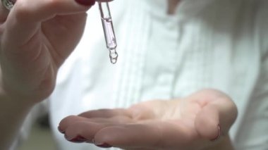 Elinde bir pipetle gerekli yağı damlatıyor. Kozmetik pipeti