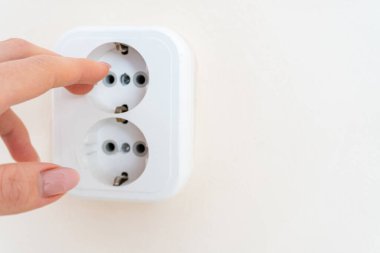 İnsan elinin yakın plan çekimi. Elektrik prizinde düğmeye basma. Prize el basma.