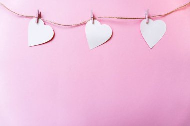 Beyaz kalpler pembe bir arka planda keten iplikte sallanıyor. Ba