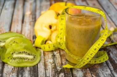 Arındırılmış gıda sağlıklı yaşam tarzı içer: Sağlıklı diyet yeşil tatlı meyveler. Arka planda elma ve kivi. Seçici odaklanma. Santimetre bandı