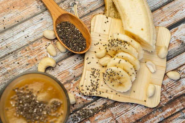 Healthy protein shake with banana, nuts and chia in a glass on w
