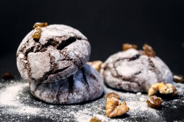 Fındıklı, kuru üzümlü ve unlu çikolatalı kurabiye. Koyu siyah arka planda çikolatalı buruşuk kurabiyeler. Noel, tarif konsepti. Siyah arka planda pudra şekerli çikolatalı kurabiyeler. 