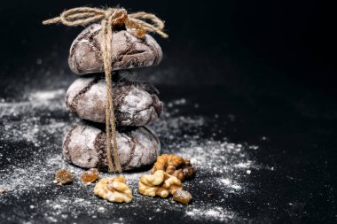 Fındıklı ve unlu çikolatalı kurabiye. Koyu siyah arka planda çikolatalı buruşuk kurabiyeler. Noel, tarif konsepti. Siyah arka planda pudra şekerli çikolatalı kurabiyeler. 