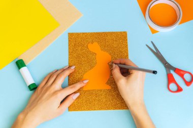 Paskalya kartları kağıttan. Mavi arka planda tavşanlı cildi selamlama kartları. Üç boyutlu. Hediye fikri, dekor ilkbaharı, Paskalya. Adım adım. Üst Manzara. İşlemci çocuk işi. Renkli tatil dekorasyonu