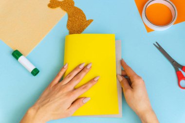 Paskalya tavşanı, çocuklar için kolay zanaatlar, renkli kâğıttan tebrik kartlarıyla bembeyaz yatıyordu. Adım adım. Bahar, Paskalya. Konsept: Paskalya için çocuk el işi. Basamaklardaki talimatlar.