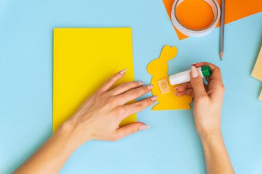 Paskalya kartları kağıttan. Mavi arka planda tavşanlı cildi selamlama kartları. Üç boyutlu. Hediye fikri, dekor ilkbaharı, Paskalya. Adım adım. Üst Manzara. Süreç çocuk zanaatı.