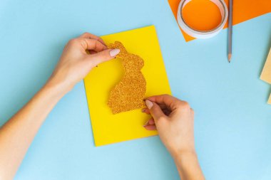 Paskalya kartları kağıttan. Mavi arka planda tavşanlı cildi selamlama kartları. Üç boyutlu. Hediye fikri, dekor ilkbaharı, Paskalya. Adım adım. Üst Manzara. İşlemci çocuk işi. Renkli tatil dekorasyonu