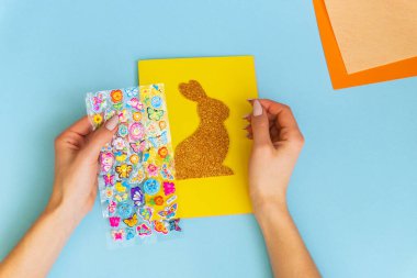 Paskalya kartları kağıttan. Mavi arka planda tavşanlı cildi selamlama kartları. Üç boyutlu. Hediye fikri, dekor ilkbaharı, Paskalya. Adım adım. Üst Manzara. İşlemci çocuk işi. Renkli tatil dekorasyonu