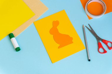 Paskalya kartları kağıttan. Mavi arka planda tavşanlı cildi selamlama kartları. Üç boyutlu. Hediye fikri, dekor ilkbaharı, Paskalya. Adım adım. Üst Manzara. İşlemci çocuk işi. Renkli tatil dekorasyonu