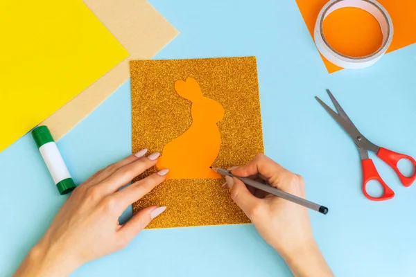 Diy Easter cards from paper. Volume greeting cards with a bunny, on blue background. 3d. Gift idea, decor Spring, Easter. Step by step. Top view. Process kid children craft. Colorful holiday decoration