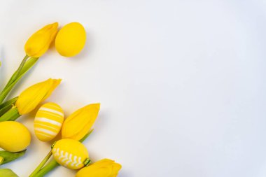 Sarı yumurtalı ve sarı laleli Paskalya arkaplanı. Kopyalama alanı olan üst görünüm. Paskalya kartpostalı. Bahar ve Paskalya bayramı yatıyordu. Asgari paskalya konsepti. Paschal tebrik kartı.