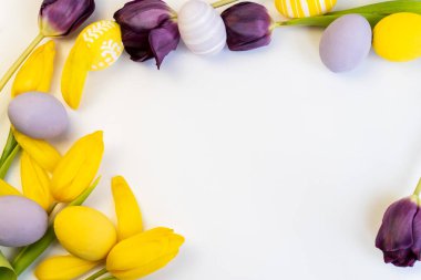 Paskalya arkaplanını tebrik ederim. Beyaz arka planda laleler ve paskalya yumurtaları. Mutlu Paskalyalar. Üst Manzara. Uzayı kopyala Paskalya bayramı tebrik kartı.. 