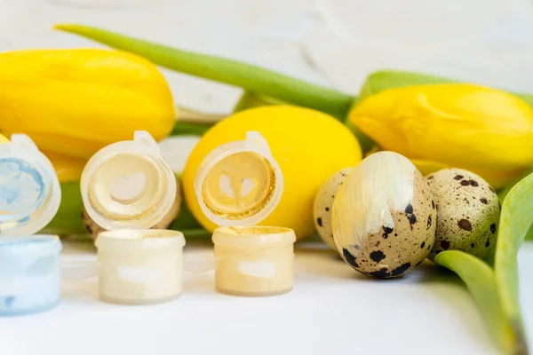 Preparing for Easter,  painting quail easter eggs. Paints, yellow  eggs and yellow tulips. Happy Easter.   Easter and holidays concept. Selective focus.