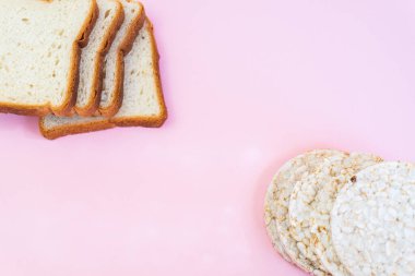 Tam teşekküllü ekmek dilimleri ve pembe arka planda şeritli gevrek pirinç gevrekleri. Yuvarlak tatlı kepekli gevrek, gevrek kraker. Diyet konsepti. Düz yatıyordu. 