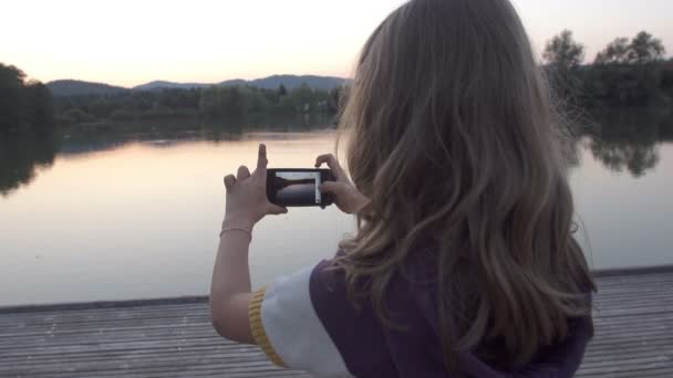 Девушка фотографирует озеро — стоковое видео