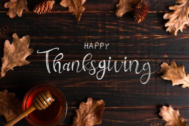 Şükran Günü selamları. Bal, baharatlar ve kuru yapraklar ahşap arka planda, üst manzara. Kaligrafik büyük harf yazımı.