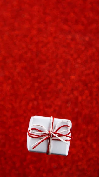 红色光泽背景上的白色小礼物 侧面有亮片 情人节的概念 复制空间 — 图库照片
