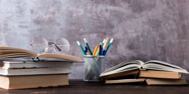 Concept to teacher's day. Pens, apple, pencils, books and glasses on table. Back to school, copy space.