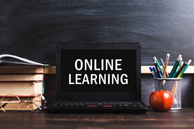Inscription on leptop screen, online learning. The concept of distance learning. Pens, pencils, books and glasses on table.