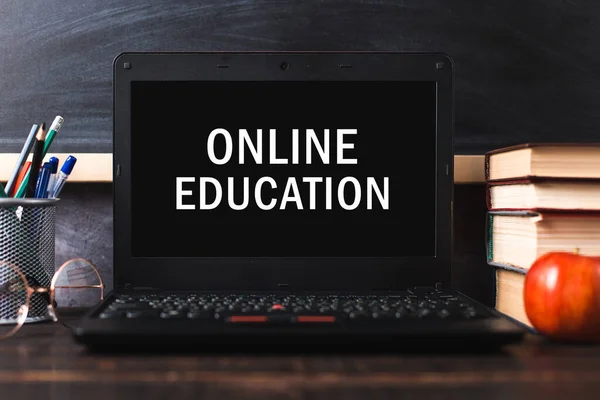 Inscription on leptop screen, online education. The concept of distance learning. Pens, pencils, books and glasses on table.