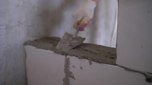 a builder applies concrete mortar to a brick