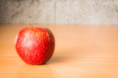 Kırmızı elma dramatik aydınlatma, ahşap bir masa üzerinde seçici odak.
