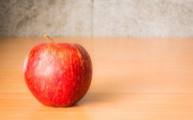Kırmızı elma dramatik aydınlatma, ahşap bir masa üzerinde seçici odak.