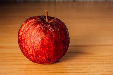 Kırmızı elma dramatik aydınlatma, ahşap bir masa üzerinde seçici odak.