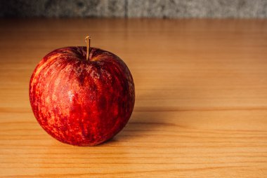 Kırmızı elma dramatik aydınlatma, ahşap bir masa üzerinde seçici odak.