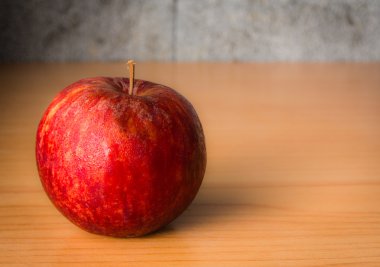 Kırmızı elma dramatik aydınlatma, ahşap bir masa üzerinde seçici odak.